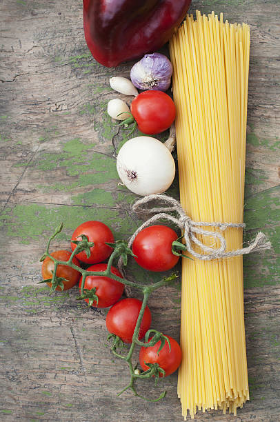 Spaghetti and vegetables on wooden background stock photo