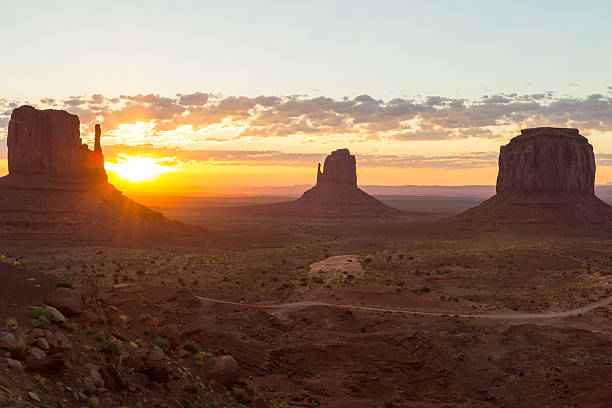 The Mittens at sunrise East and West Mitten Buttes and Merrick Butte in Monument Valley. The sun is rising. There are only a few clouds in the sky. david merrick photos stock pictures, royalty-free photos & images