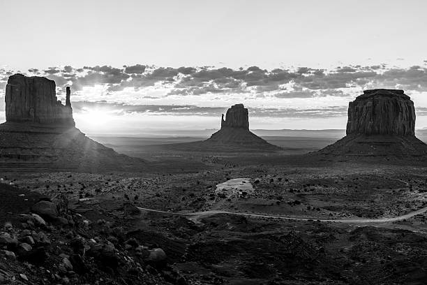 The Mittens in monochrome East and West Mitten Buttes and Merrick Butte in Monument Valley in monochrome. The sun is rising. There are only a few clouds in the sky. david merrick photos stock pictures, royalty-free photos & images