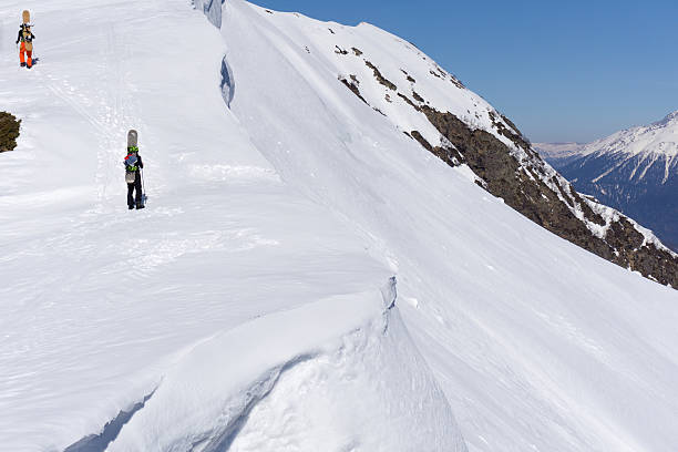istock Snowboarders walking uphill for freeride 486683846