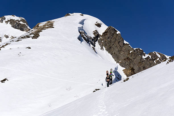 istock Snowboarders walking uphill for freeride 486684382