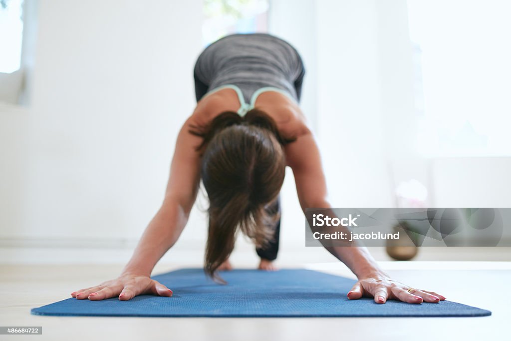 Woman doing Adho Mukha Svanasana yoga pose Portrait of woman practicing downward dog pose on yoga mat.  Fitness female in Adho Mukha Svanasana pose. 2015 Stock Photo