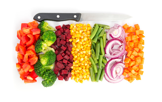 Cut colorful vegetables in line with knife on white background