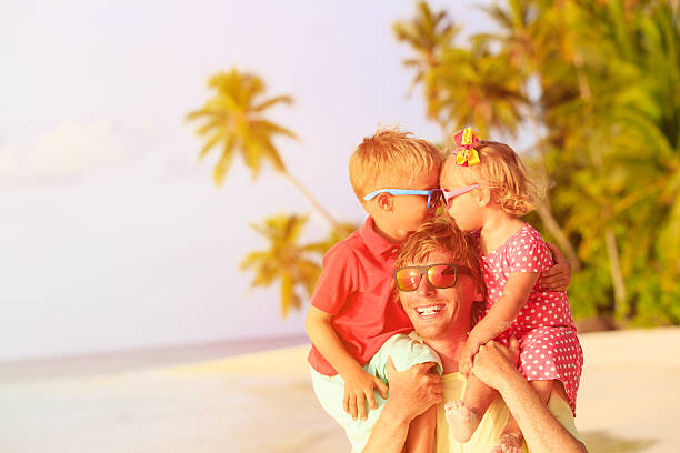 istock happy father with kids on shoulders having fun at beach 486685362
