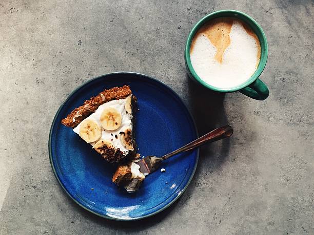 Slice of banoffee pie on plate with fork, espresso drink