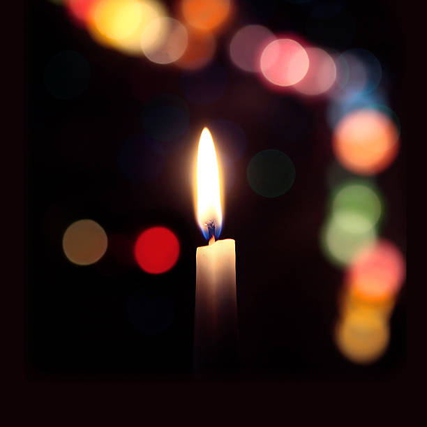 istock flame of a candle on a dark background with colored bokeh 486689911