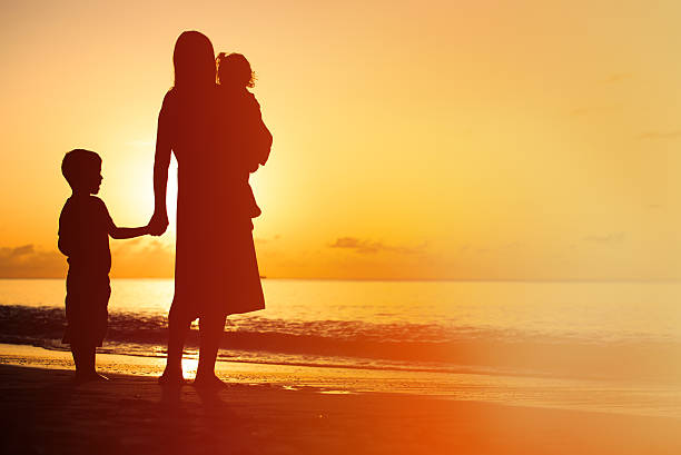 istock mother and two kids walking on beach at sunset 486690648