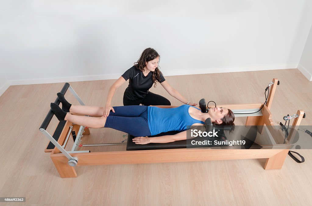 Woman And Instructor In Reformer Bed Pilates Stock Photo