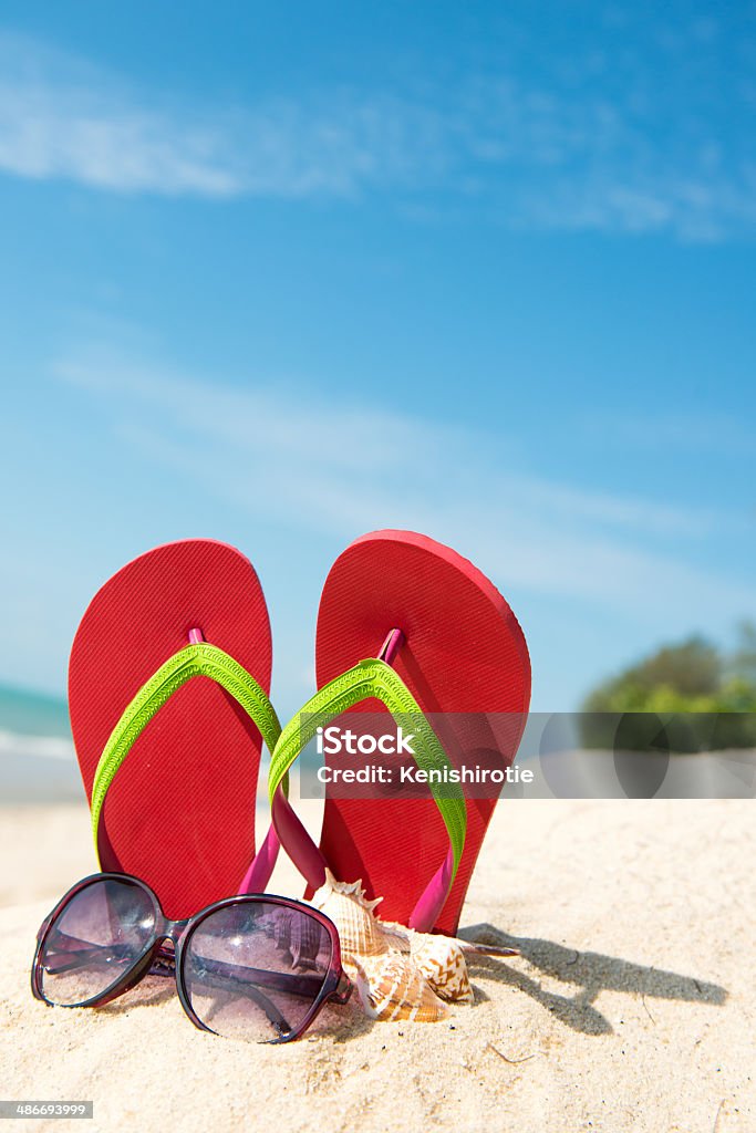 Summer beach Red flip flop and sunglasses on beach against clear blue sky Flip-Flop Stock Photo