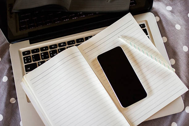 istock blank cell phone, diary and laptop on the bed 486695252