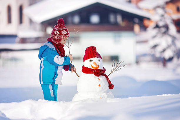 bellissimo bambino edificio pupazzo di neve felice nel giardino d'inverno - garment snow little boys child foto e immagini stock