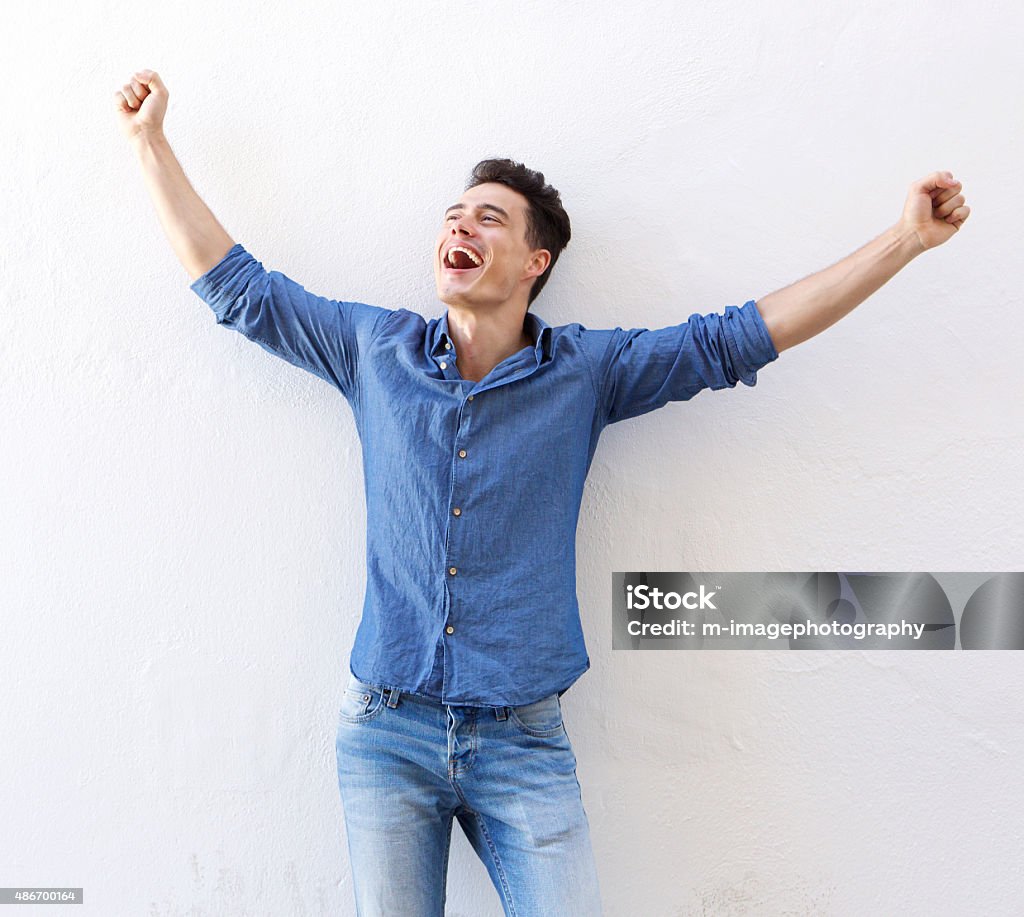 Cheerful young man with raised arms celebrating Portrait of a cheerful young man with raised arms celebrating Men Stock Photo