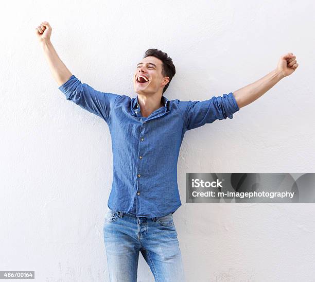 Cheerful Young Man With Raised Arms Celebrating Stock Photo - Download Image Now - Men, Arms Raised, Happiness