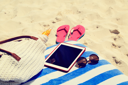 Beach bag, slippers and touch pad on the beach, summer vacation