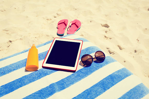 istock Suncream, slippers and touch pad on the beach 486702838