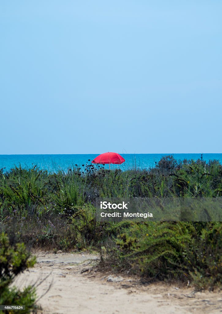 Isolated red umbrella on beach Isolated red umbrella on the beach 2015 Stock Photo