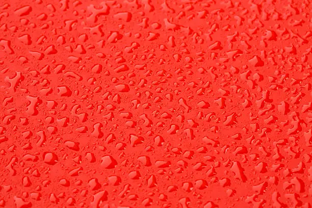Raindrops background. Close up. Ice cold,  Red surface covered with water drops condensation texture. 