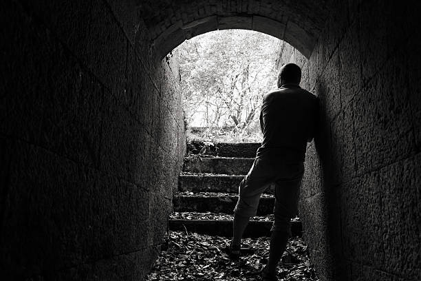 istock Young man stands in dark tunnel with glowing end 486722306