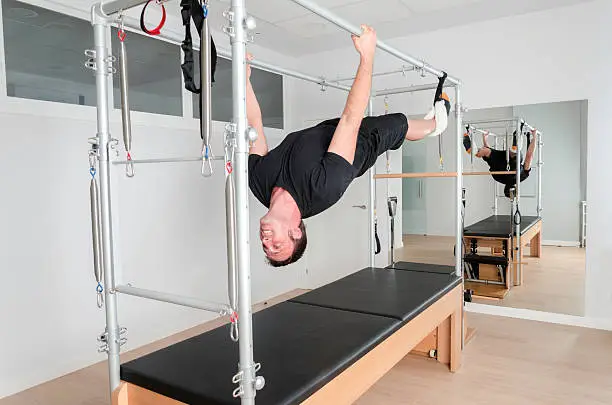 Pilates aerobic instructor man in cadillac fitness exercise