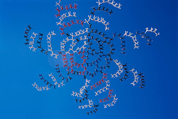 Large group of skydivers flying in formation of flower against blue sky