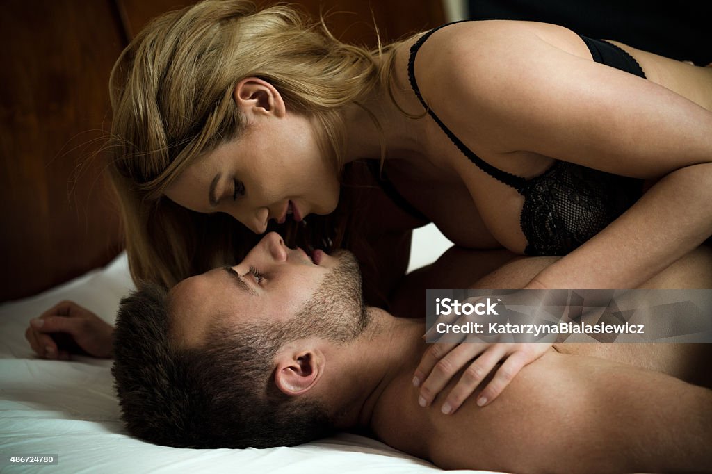 Woman seducing man Woman seducing man lying on him in sexy lingerie Couple - Relationship Stock Photo
