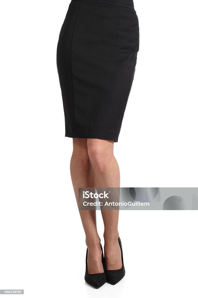 Bottom half of woman wearing pencil skirt on white A photograph of a young businesswoman's legs.  She is visible from the waist down and wears a black pencil skirt and nylons.  Her skirt does not quite reach her knees.  It is pressed, but there are wrinkles near the bend of her waist.  Her shoes are stylish black flats, and her feet are pointed playfully toward the camera.  She is a thin woman and has positioned herself with relaxed knees, the left one slightly in front of the right one, but her legs are not crossed.  She is isolated on a white background, which contrasts her dark clothing nicely. Black Color Stock Photo