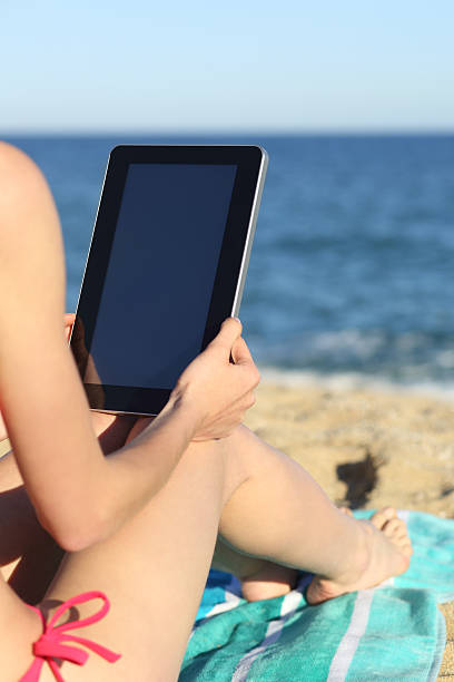 istock Woman on vacations reading a tablet on the beach 486729317