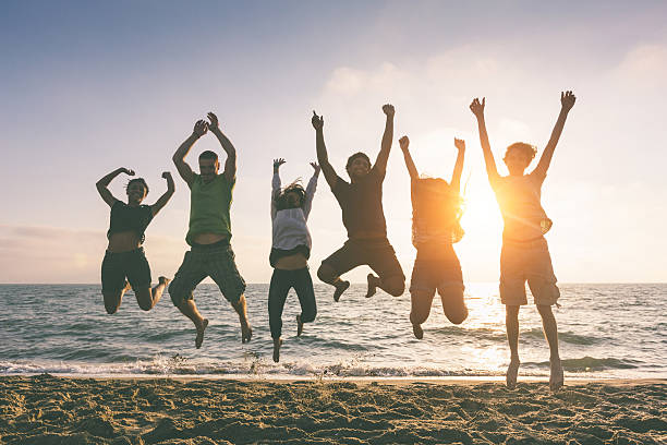 istock Multiracial Group of People Jumping at Beach, Backlight 486729439