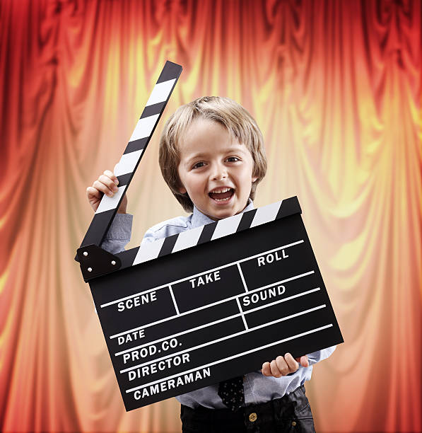 boy sosteniendo un clapper placa en una sala de cine con montaje tipo auditorio - fotos de acomodador cine fotografías e imágenes de stock