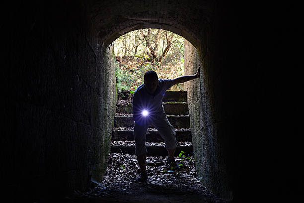 istock Young man with flashlight enters the stone tunnel 486737768