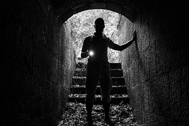 istock Young man with a flashlight in stone tunnel 486738052