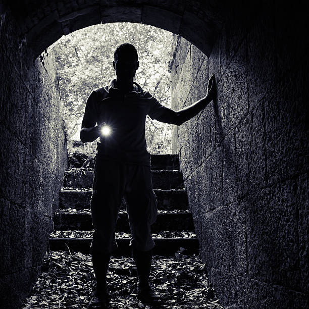 istock Young man with a flashlight enters the stone tunnel 486738184