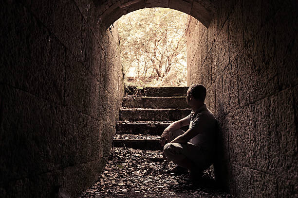 istock Young man sits inside of dark stone tunnel 486738562