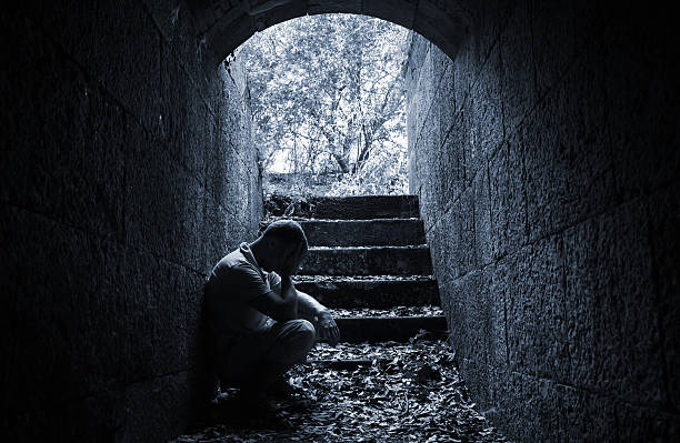 istock Young sad man sitting inside of dark stone tunnel 486739020