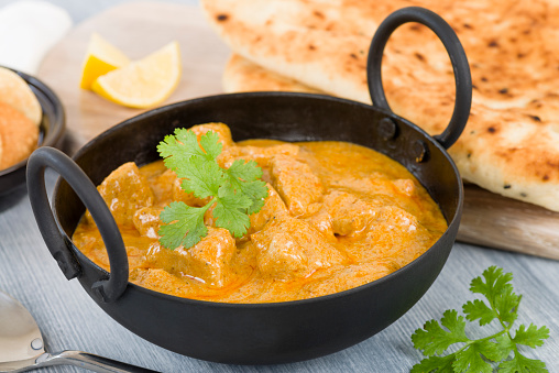 Chicken Korma - Chicken on a mildly spiced creamy sauce served with naan bread and poppadoms. Indian cuisine.