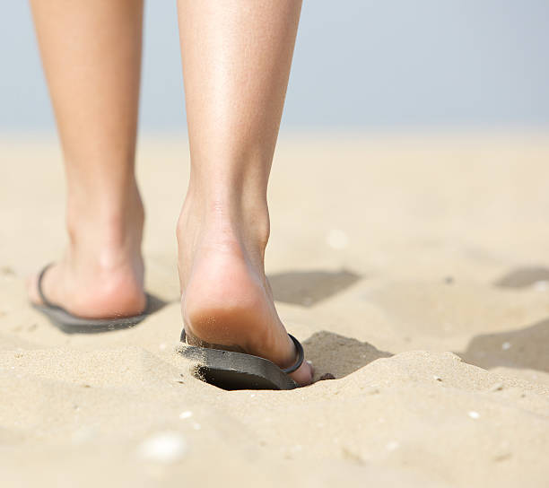 istock Woman walking in slippers on sand 486743367
