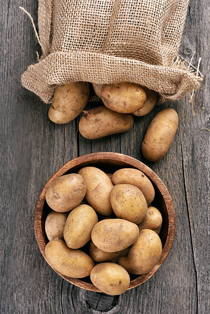 Raw potatoes on wooden table stock photo
