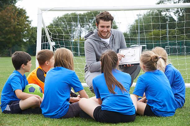 entrenador personal que habla de escuela primaria del equipo de fútbol - soccer child coach childhood fotografías e imágenes de stock