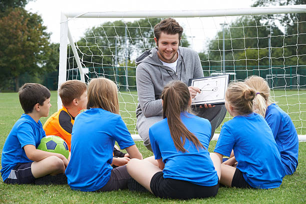 Coach Giving Team Talk To Elementary School Soccer Team Coach Giving Team Talk To Elementary School Soccer Team drive ball sports photos stock pictures, royalty-free photos & images