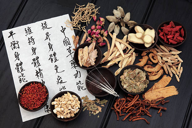 Traditional Chinese Medicine Acupuncture needles with chinese herbal medicine selection and mandarin calligraphy script on rice paper describing the medicinal functions to maintain body and spirit health and balance body energy. chinese script photos stock pictures, royalty-free photos & images