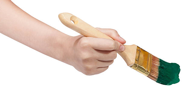 istock hand with flat paintbrush paints in green paint 486748800