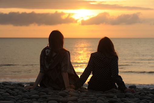 Girls Watching the Sun Go Down at the Beach