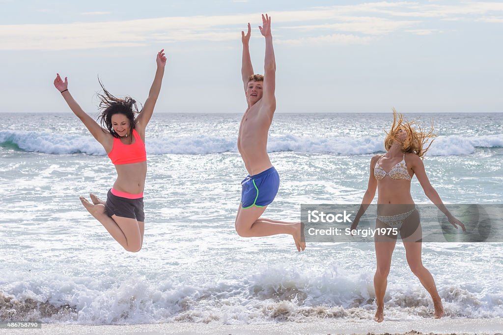 young men jumping on the beach young men jumping on the beach against the sea 2015 Stock Photo