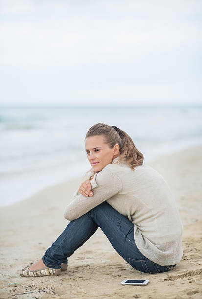 istock calm young woman sitting on cold beach 486763667