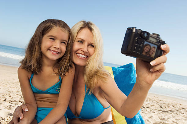 Mother And Daughter Taking Self Portrait On Beach