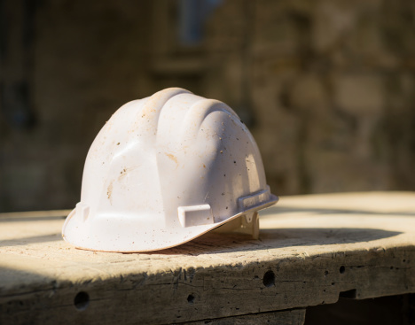 A white hardhat on a wooden surface at a construction site.