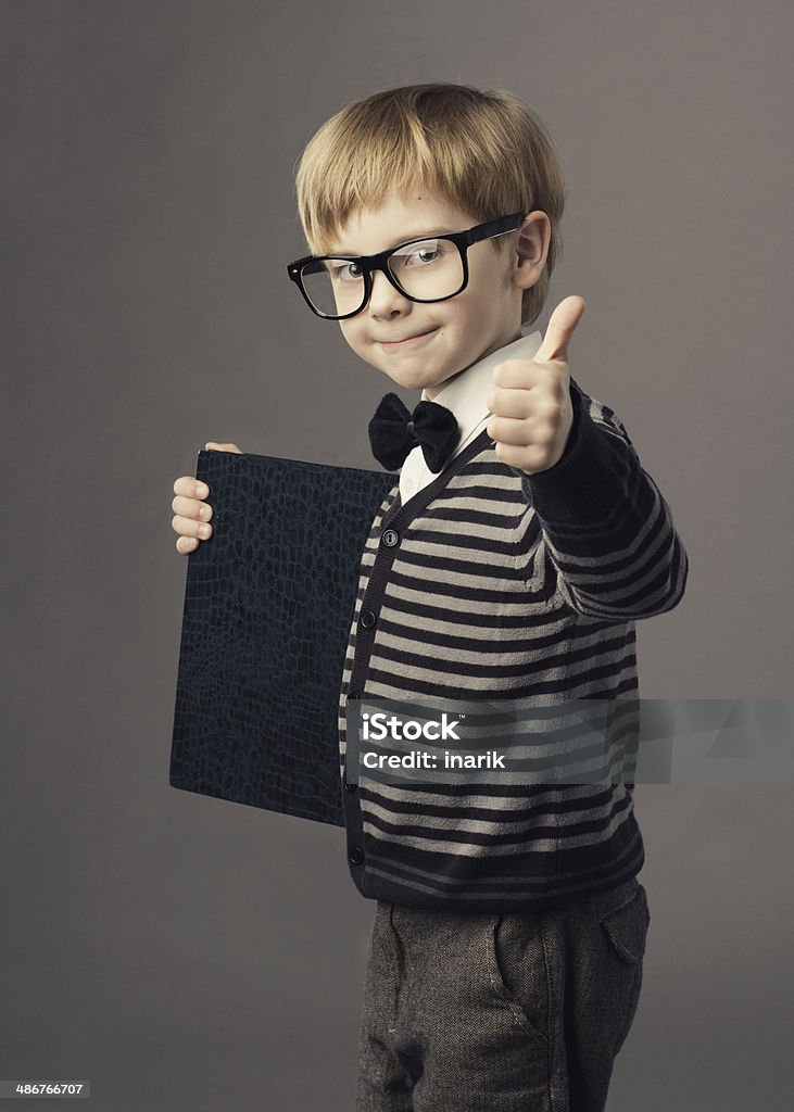 boy little smart child in glasses showing blank card certificate boy little smart child in glasses showing blank card certificate, school education advertisement. 6-7 Years Stock Photo