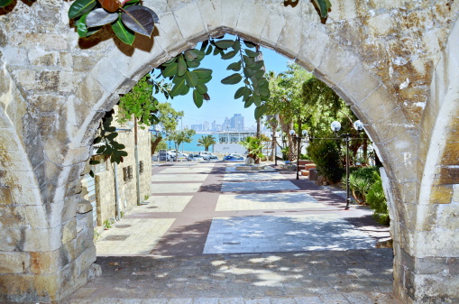 Old stone arches with the The Tel Aviv sky line background in Jaffa, Israel