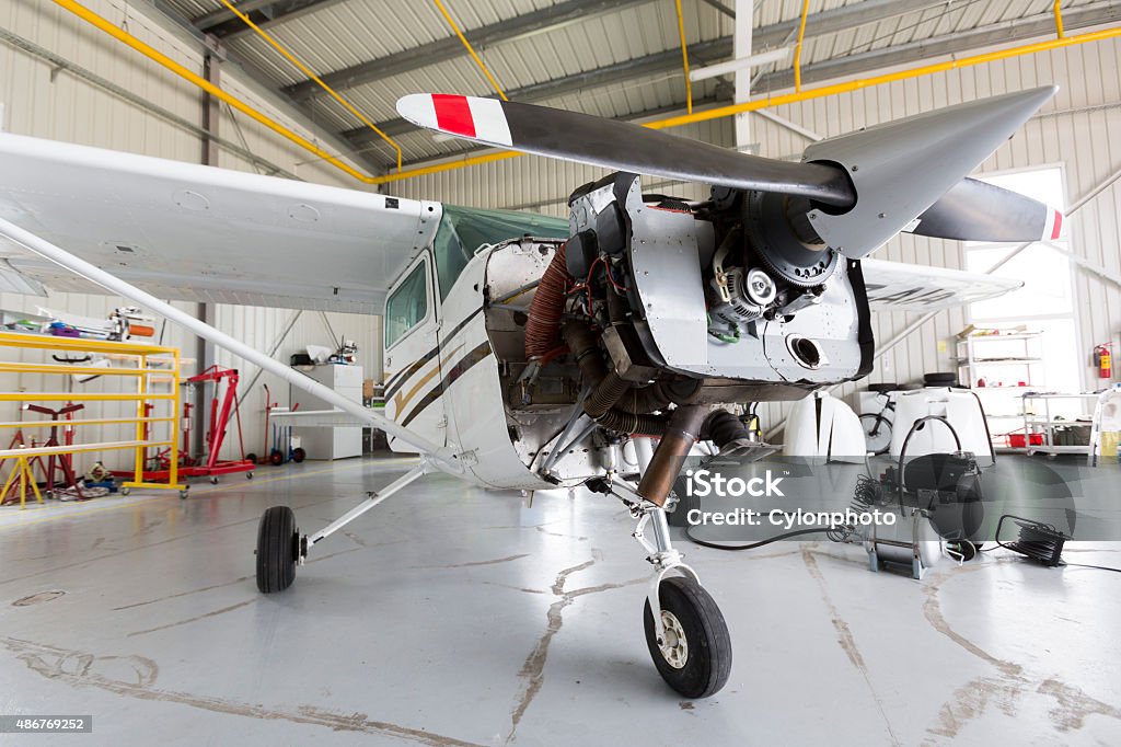 Repairing small propeller airplane Small two-seated propeller airplane is being repaired in a hangar at the airport. 2015 Stock Photo