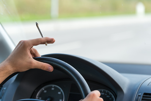 Close-up of a men driving and smoking joint 